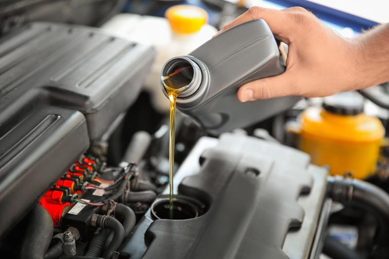 mechanic pouring synthetic oil into car engine