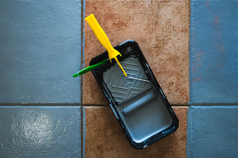paint roller and brush on tile floor
