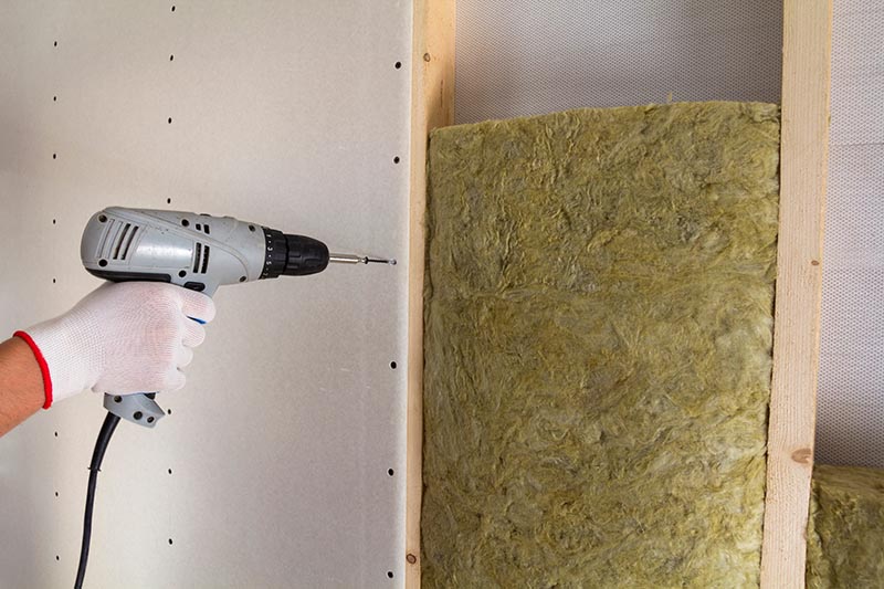 person fastening drywall with fiberglass
