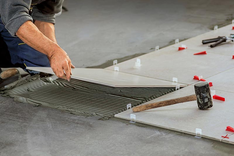 person installing ceramic tiles on the floor