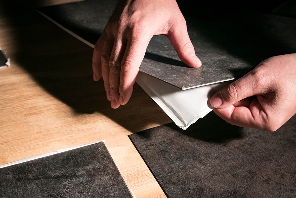 person removing back cover of peel and stick tile