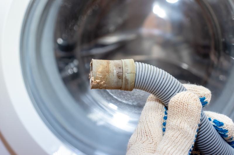 plumber holding a kinked drain/broken flexible drain hose of washing machine
