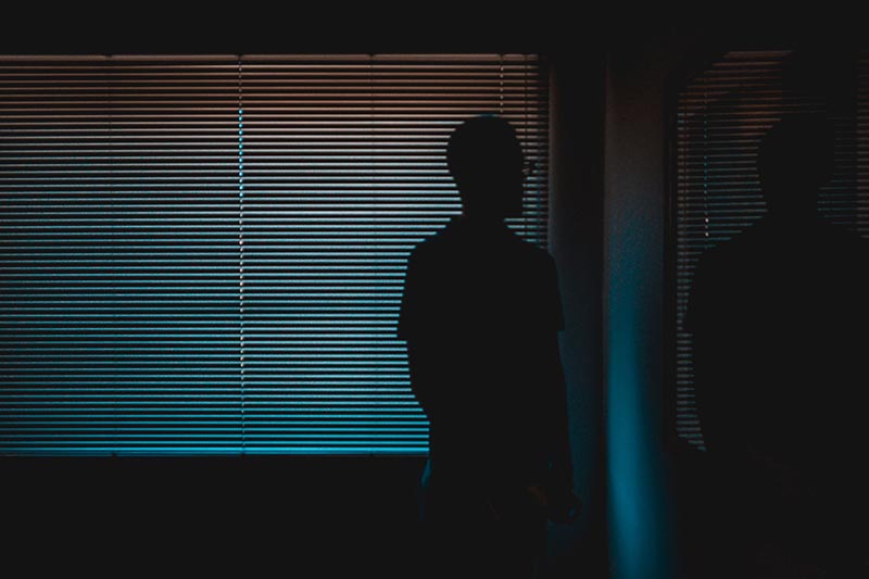 silhouette of a person near the window with blinds