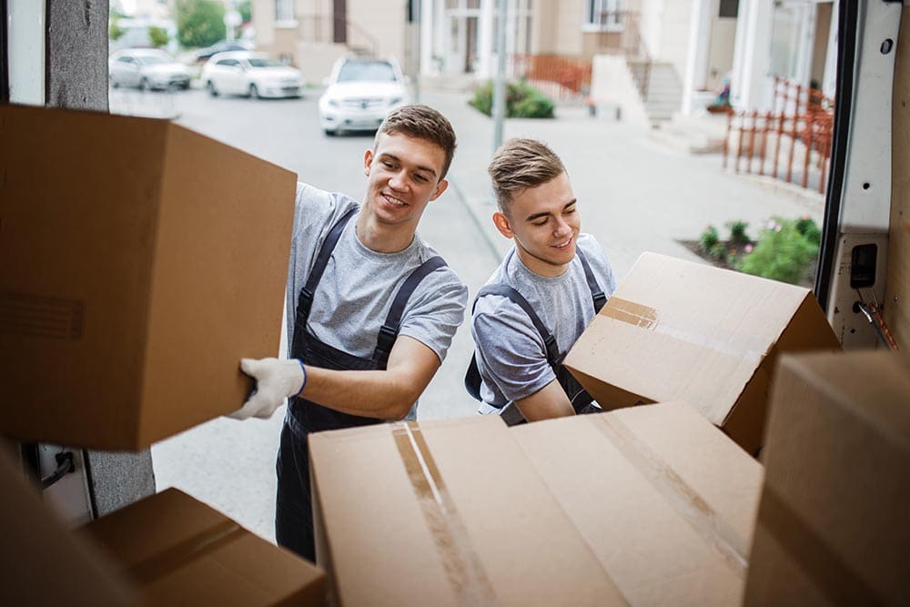 two movers smiling while unloading boxes