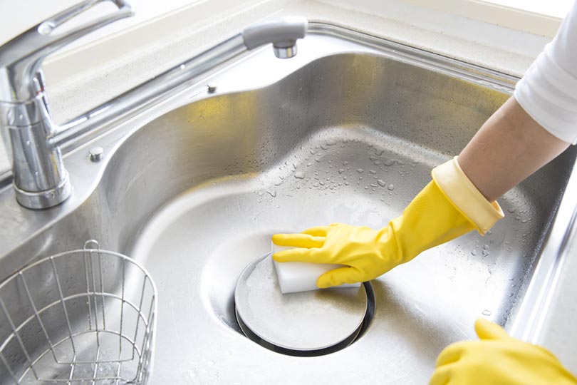 woman cleaning the stainless steel kitchen sink