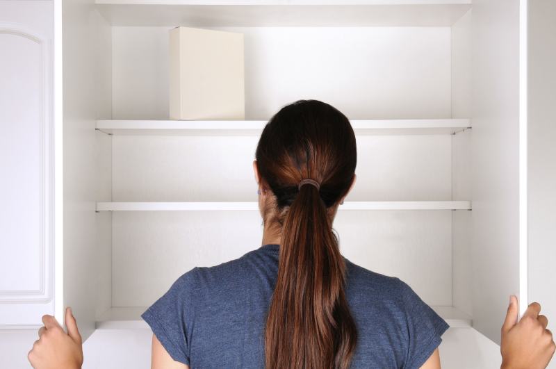 woman looking in an empty pantry at kitchen cabinet
