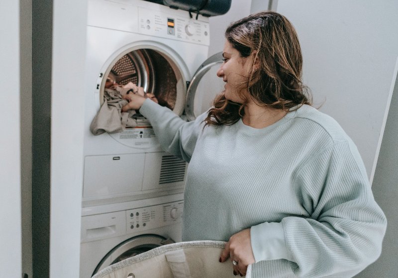 woman putting laundry into dryer machine