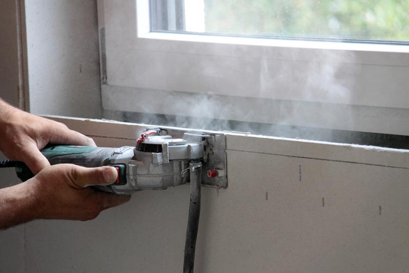 worker cutting drywall with electric hand saw