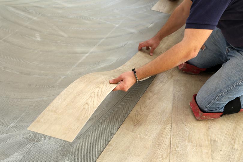 worker installing new vinyl tile floor