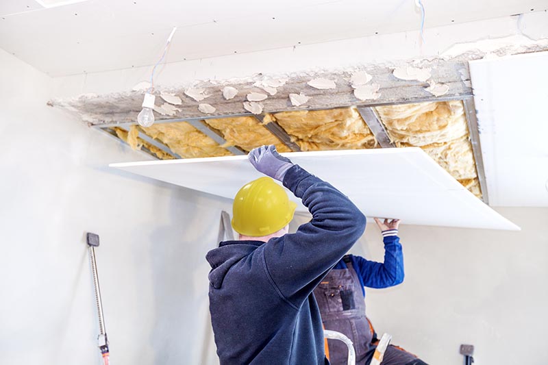 workers carrying drywall for ceiling