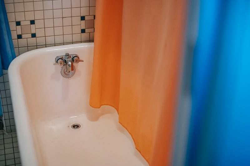 Bathtub with orange and blue shower curtain