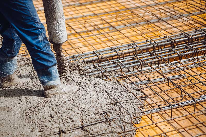 Construction worker pouring cement or concrete with pump tube
