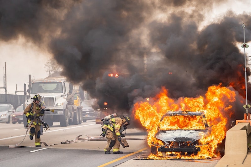 Firefighters extinguishing burning car