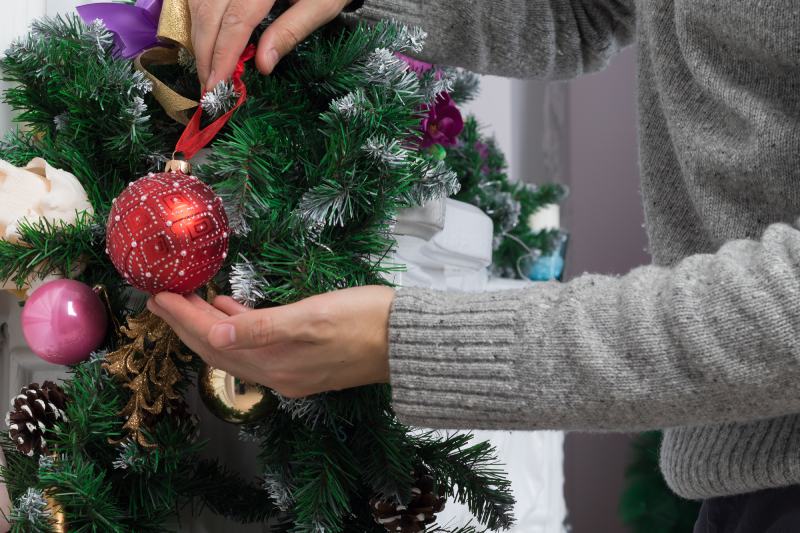 Man's hands decorating mantel with christmas garland, baubles and pine cones