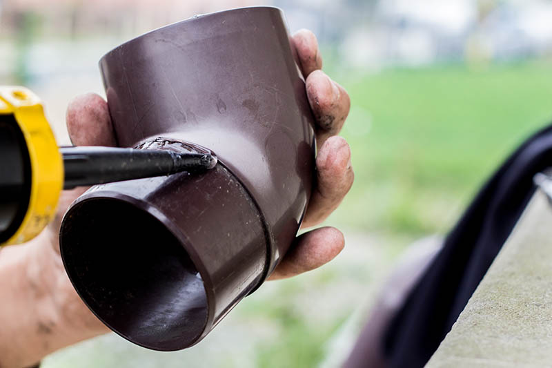 Men's hands lubricate the gutter with a sealing agent