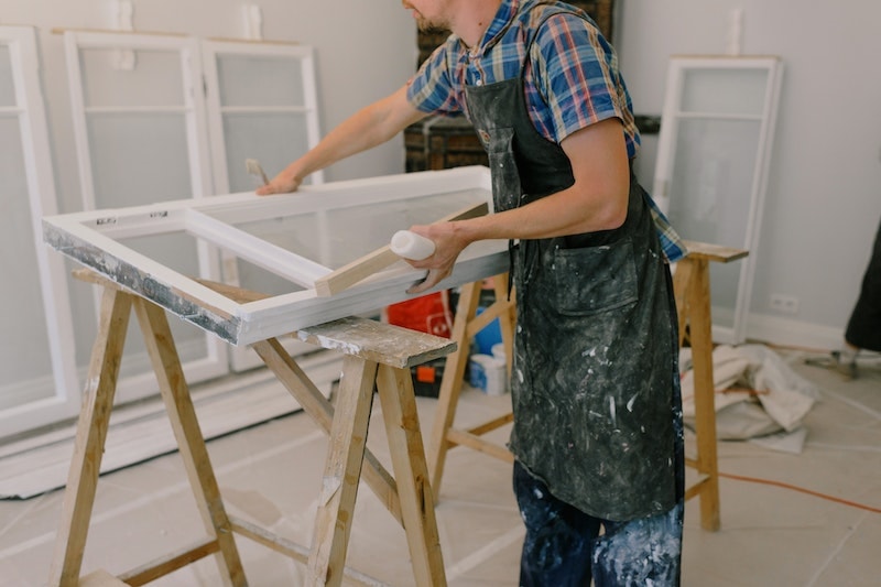Painter painting white window frame