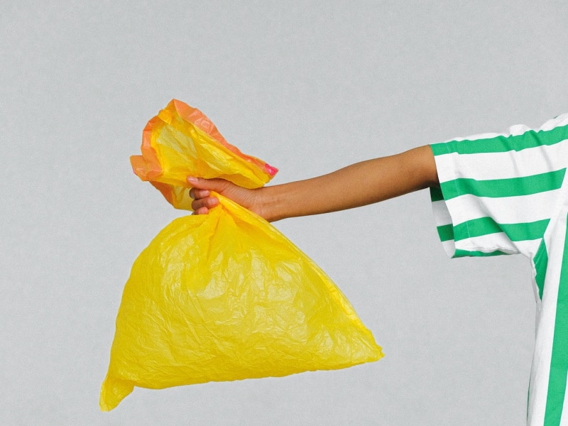 Person holding out a yellow trash bag