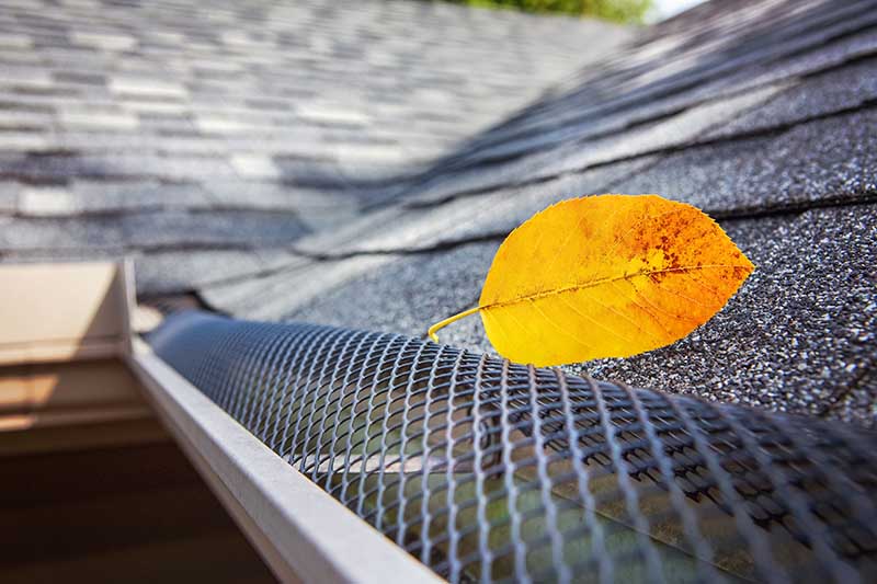Plastic guard over gutter on a roof with a leaf stuck on the outside