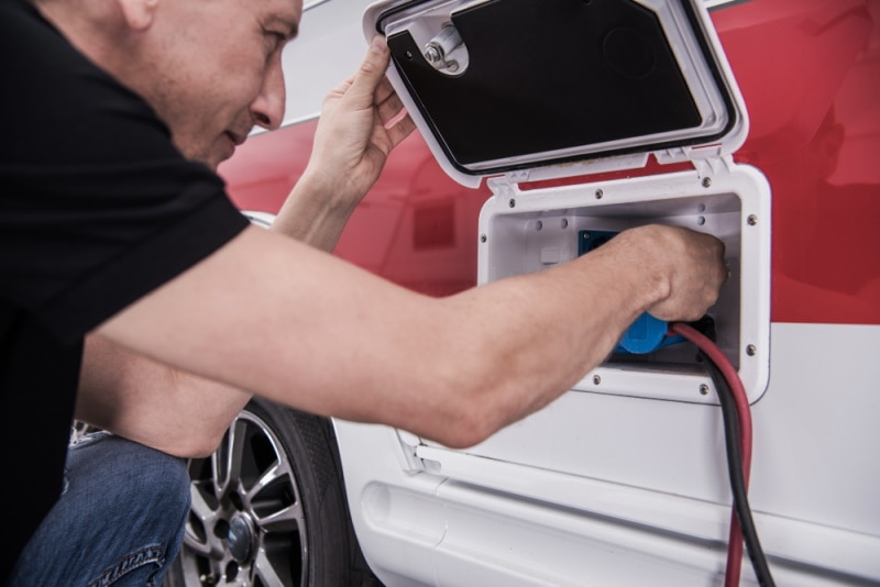 RV Vehicle Owner Plugging in Electricity