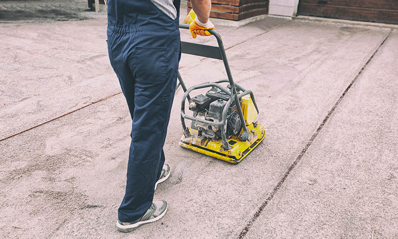 The worker tamping a gravel by the vibration plate