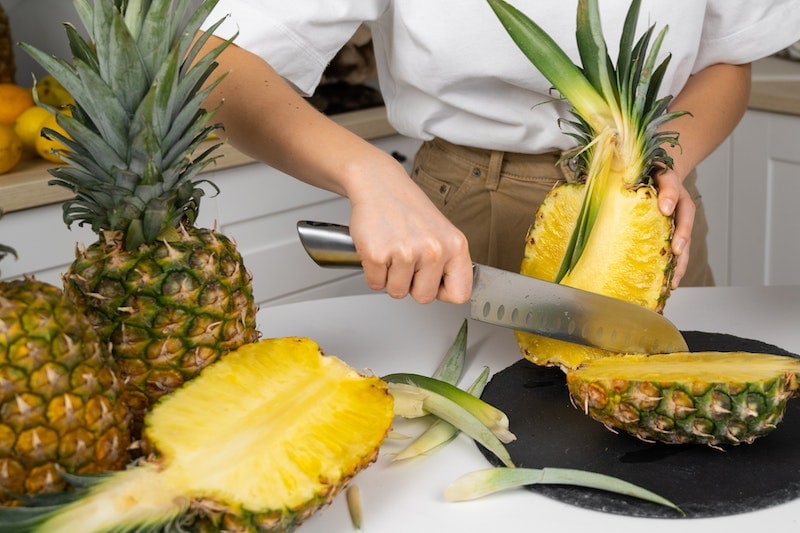 Woman slicing a pineapple with knife
