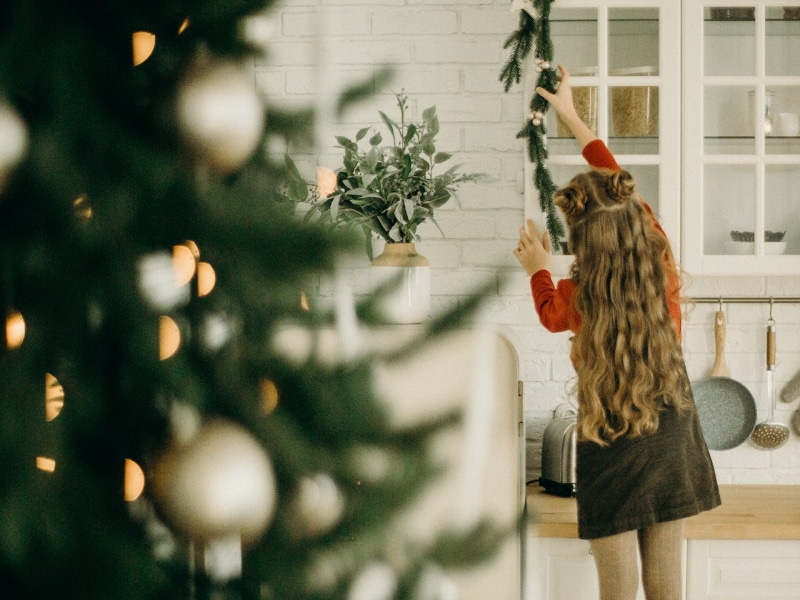 Young girl hanging garland in kitchen