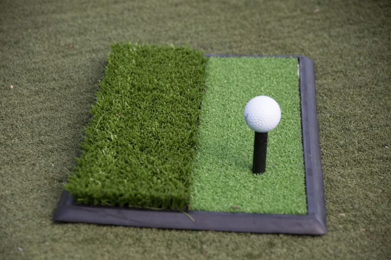 a golf ball on a tee on fake golf course grass