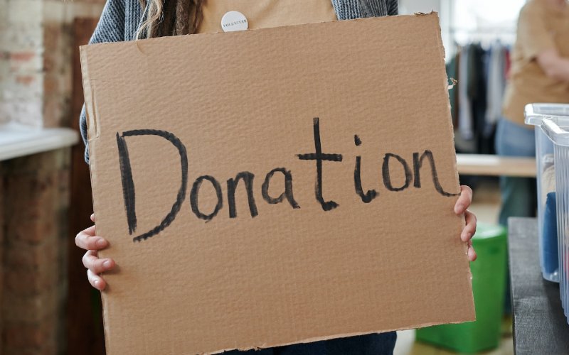 a person holding a sign for donations
