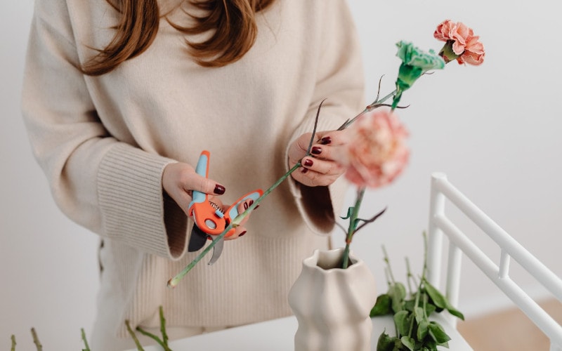 a person using pruning shears to cut flower stems