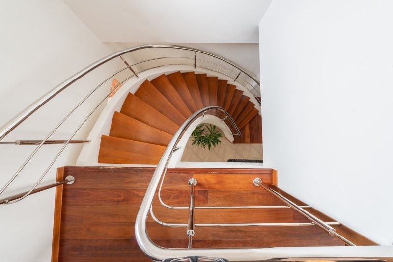 a wood curved stairs with metal railings