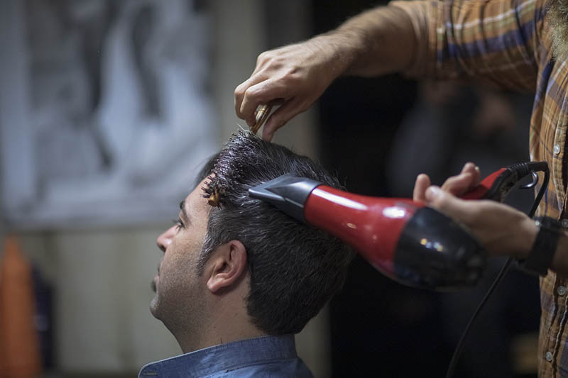 blowdrying man's hair at the barbershop