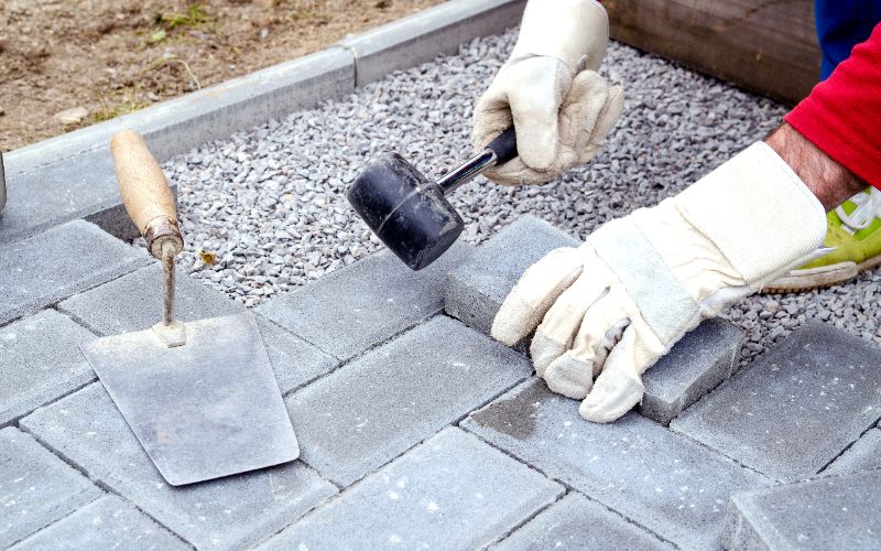 bricklayer laying down porous pavers for patio