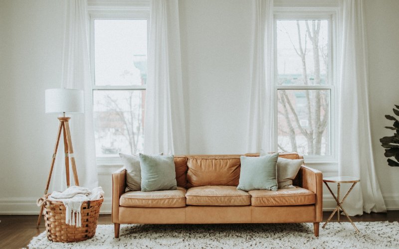 bright living room with high curtains and leather sofa