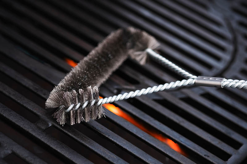 cleaning outdoor glass grill with a wire brush