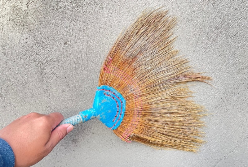cleaning wall with broom
