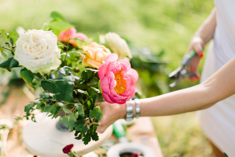 close-up on hands of young women decorating beautiful bouquet of fresh summer yellow and white roses