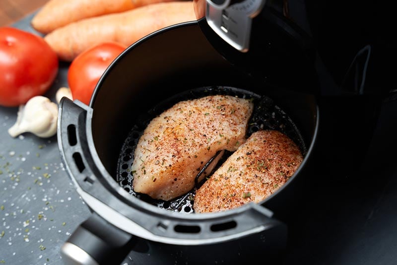 cooking skinless chicken breast with spices in an air fryer