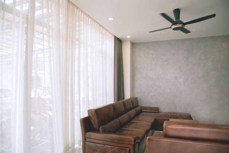 floor to ceiling curtains in living room with leather sofa