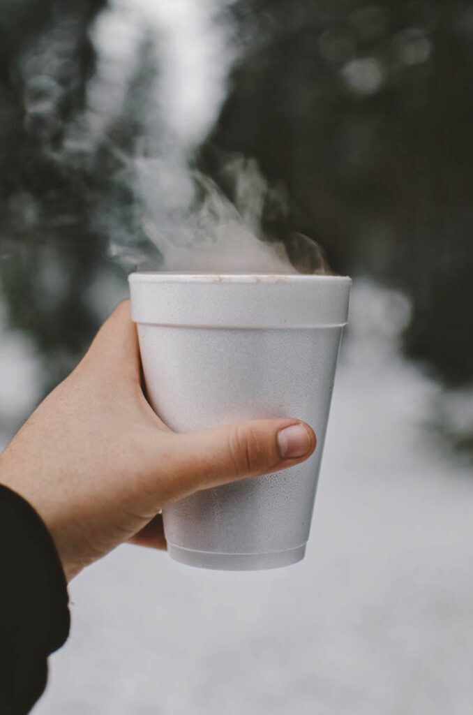 hand holding a drink on a styrofoam cup