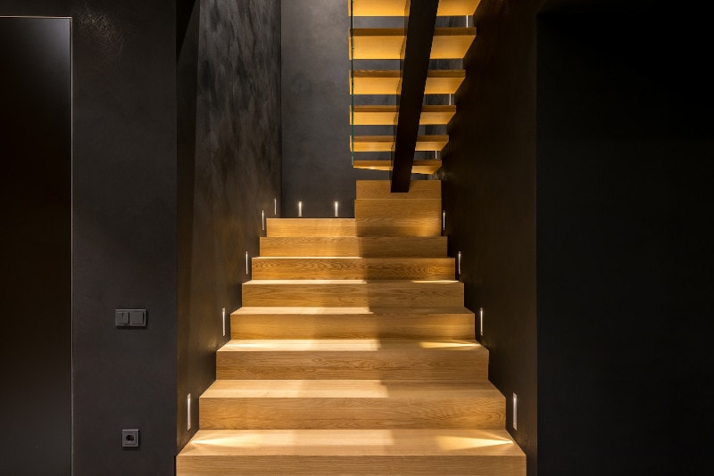 illuminated wood staircase enclosed by dark walls