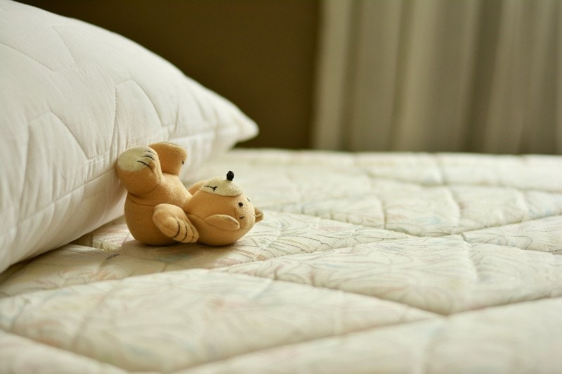 kid's stuffed toy on the bed by the pillow