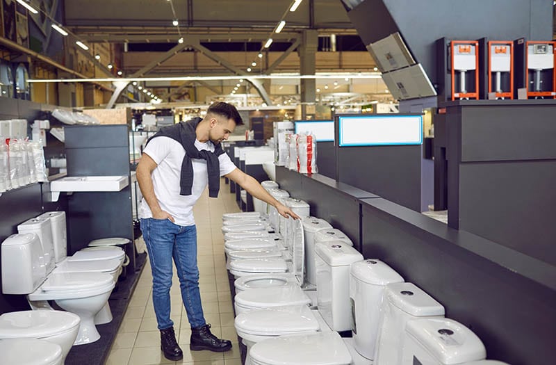 male customer looking at white flush toilets