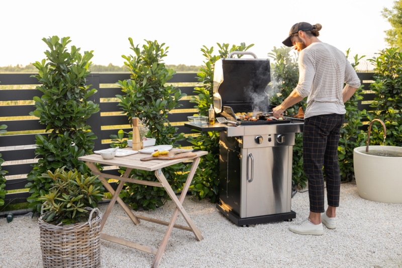 man cooking in gas griller