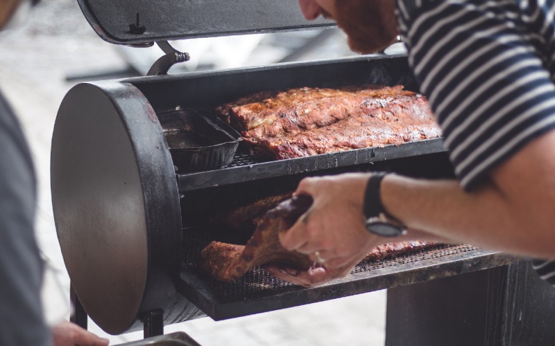 man grilling barbecue in bbq smoker