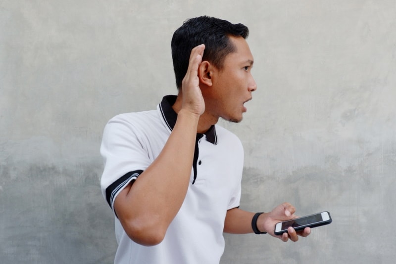 man holding phone hearing something