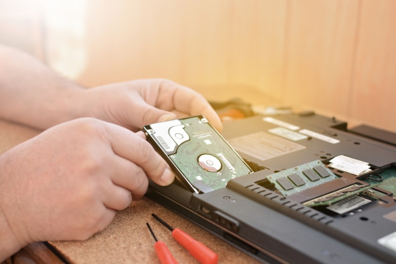 man installing hard drive in laptop
