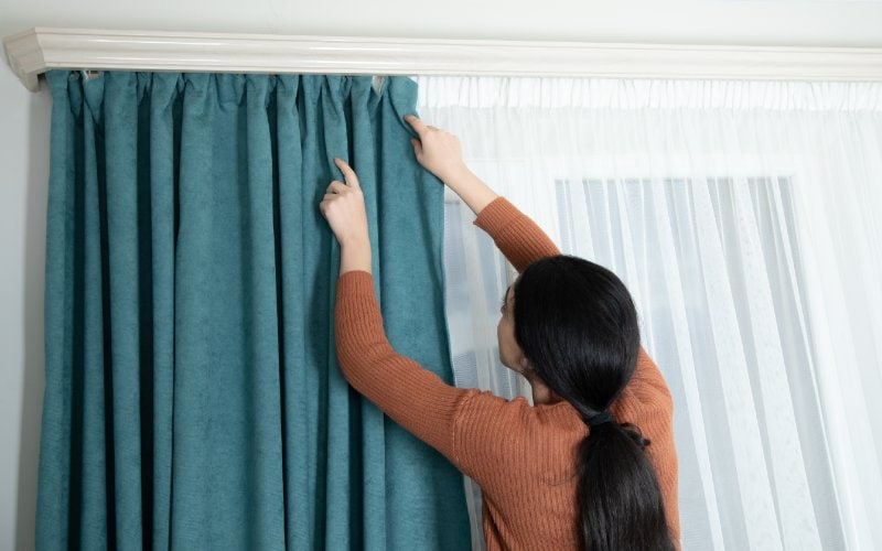 person hanging curtains