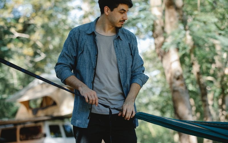 person stretching hammock between trees