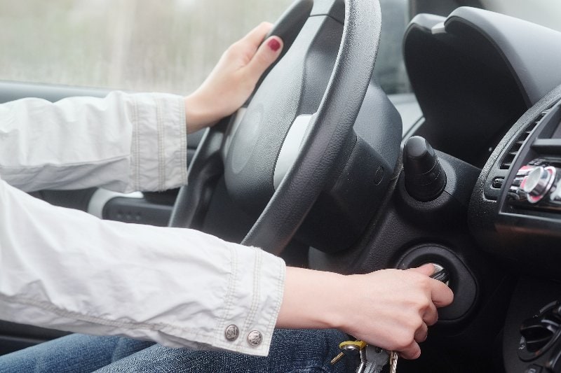 person turning the key in the ignition of the car