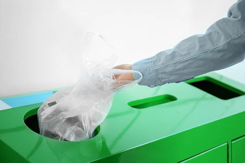 throwing plastic bag into litter bin outdoors